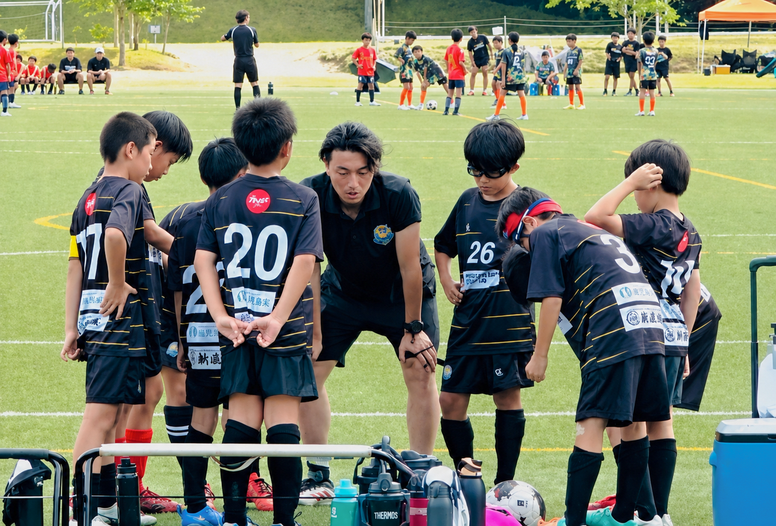 コーチが子どもたちにサッカーの作戦やプレーを指導している様子
